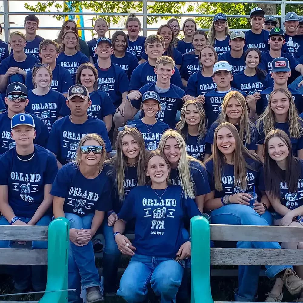 Large group of students wearing matching custom navy blue FFA t-shirts posing in bleachers.